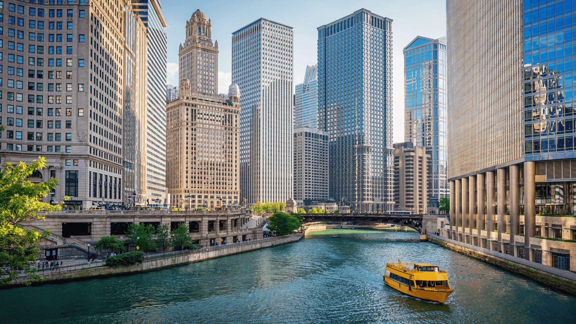 a yellow boat traveling down a river in front of tall buildings in Chicago