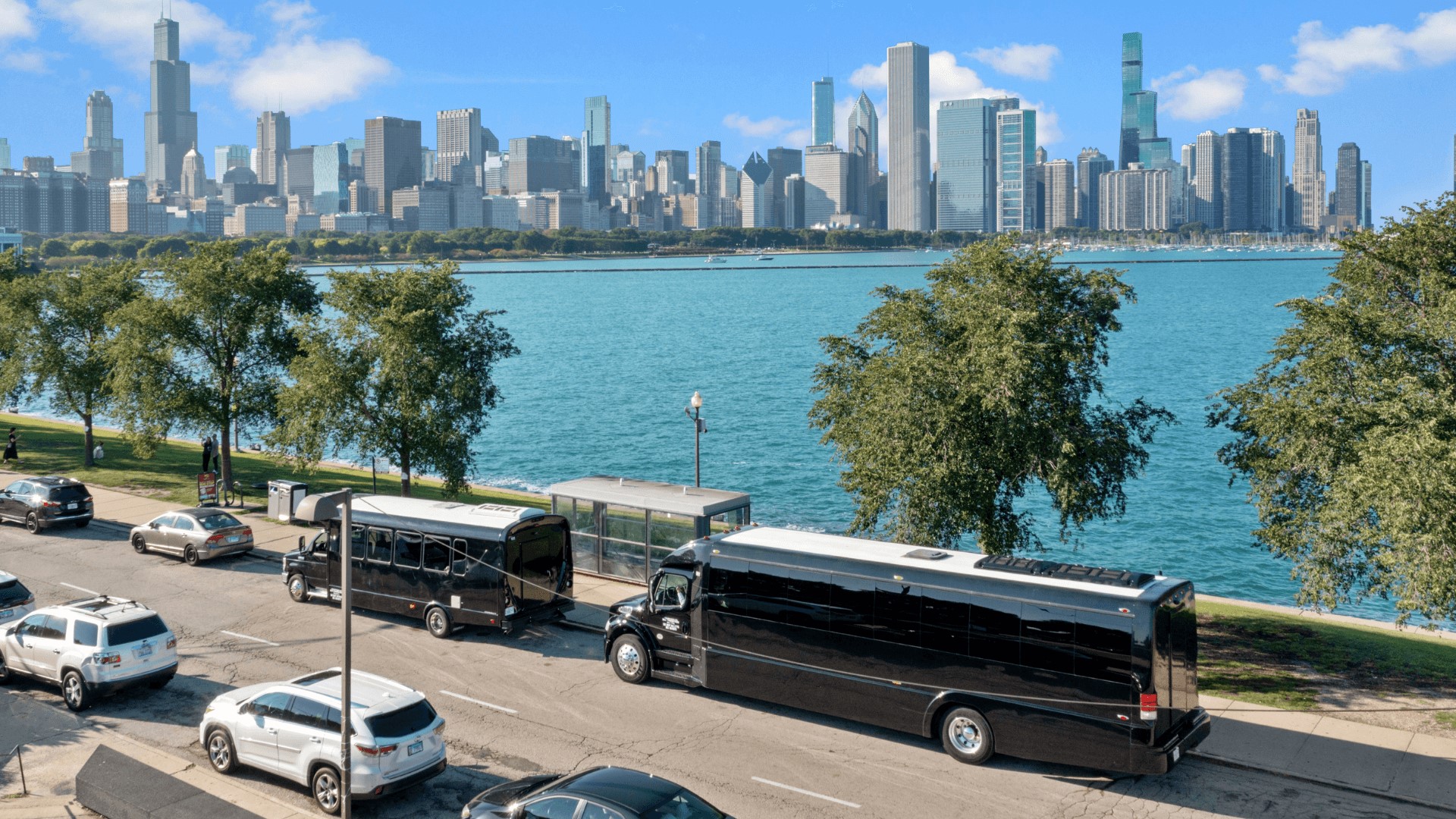 several buses are parked on the side of the road with the Chicago skyline in the background