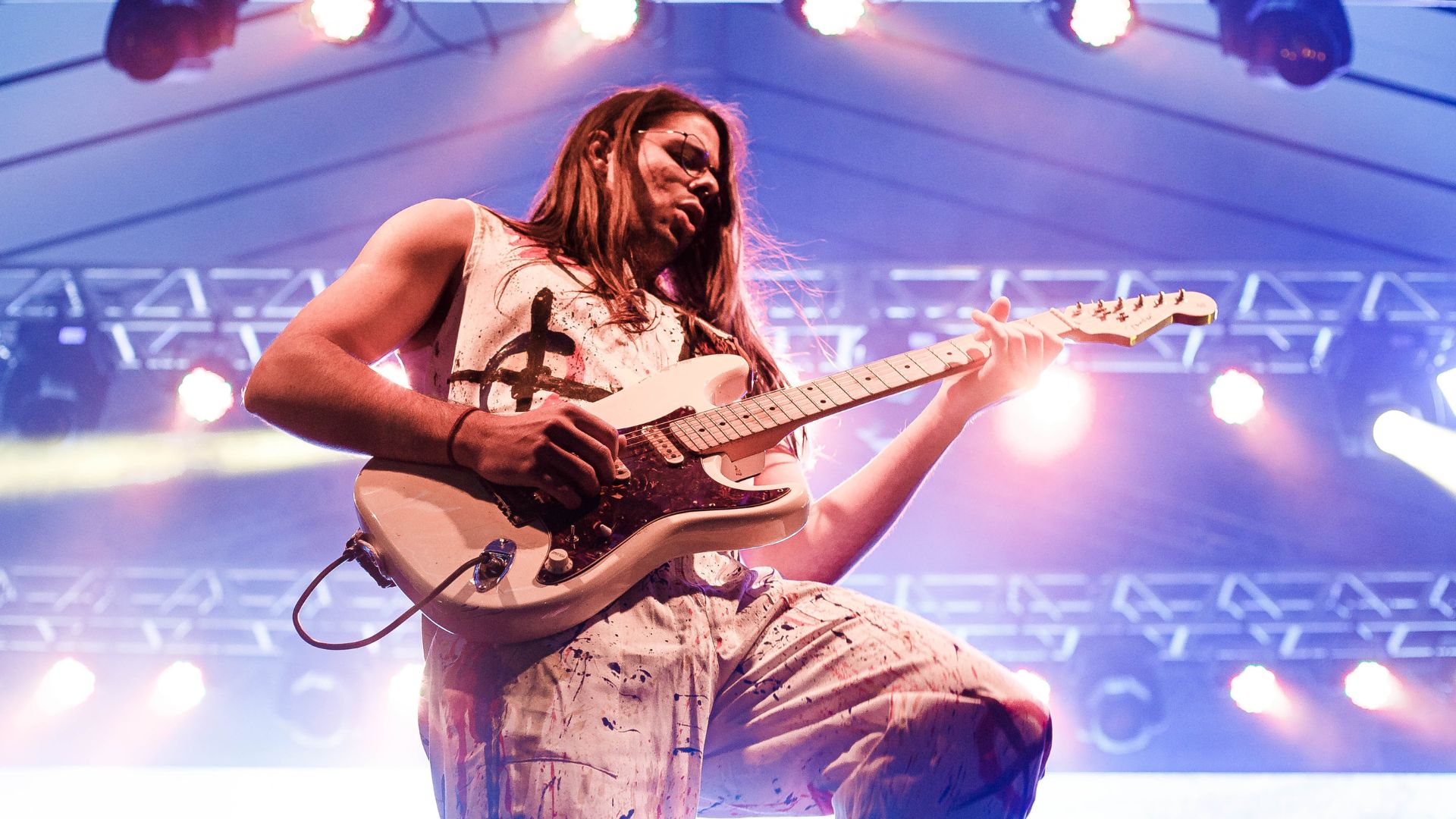 a person with long hair playing an electric guitar