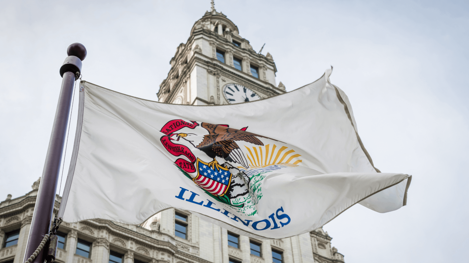 The illinois flag flutters in the wind in front of the state capitol building in chicago